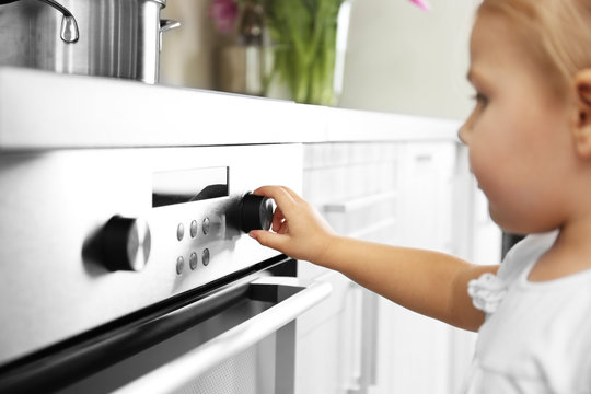 Little girl playing with electric stove in kitchen