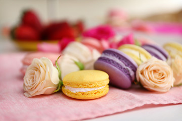 Fresh macaroons and roses on the table indoors