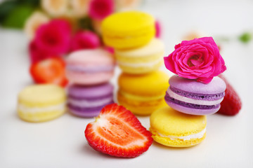 Macaroons with roses and strawberries on white background