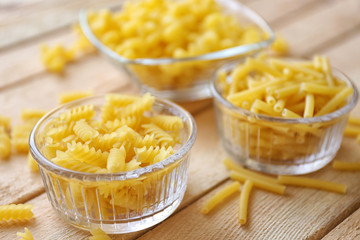 Fusilli pasta in glass bowl on wooden table