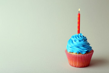 Birthday cupcake with candle on color background