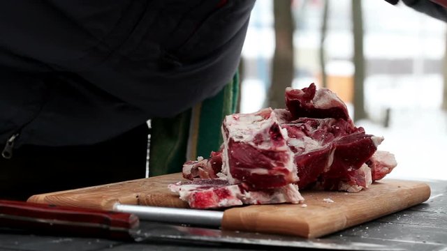 Cooking soup from lamb. A man cutting mutton on a chopping board on the pieces.