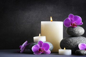 Obraz na płótnie Canvas Composition of spa pebbles, flowers and candles on grey background