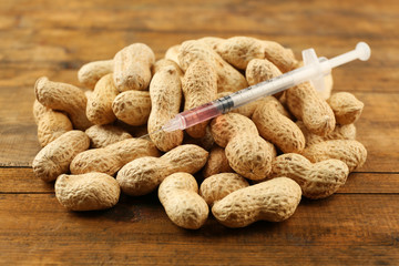 Syringe and peanuts on wooden table