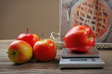 Apples with digital kitchen scales on wooden table. Cooking apple cake concept