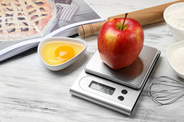 Apple with digital kitchen scales on wooden table. Cooking apple cake concept