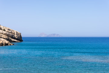 Naklejka premium The bay of Matala in south-central Crete. In the Libyan Sea, the island Paximadia. In the foreground, the cliff of the bay. Matala is known as a hippie destination from the seventies