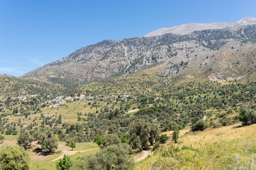Fototapeta na wymiar On the old road to Rethymnon in springtime. View to the mountain village Kouroutes on Crete. In the background, the Ida mountain range with the Psiloritis as the highest elevation on Crete 