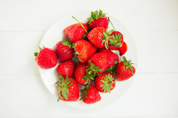 Strawberry on plate on white wooden background with copyspace. Healthy food concept. Fresh summer background.