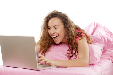 Young happy woman chatting on her laptop on the bed