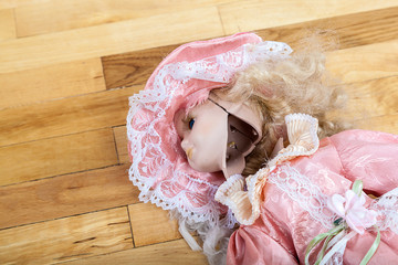 Broken doll on a wooden floor.