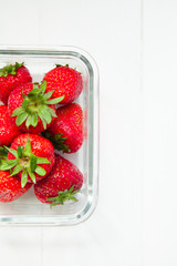 Strawberry snack in glass lunch box on white wooden background with copyspace. Healthy food concept. Take away food. Fresh summer background.