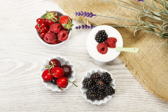 Frutos rojos, fresas, ar&aacute;ndanos, frambuesas, guindas dentro de cuencos sobre una mesa de madera &uacute;stica. Vsta superior