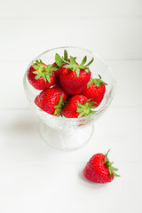 Strawberry in glass cup on white wooden background with copyspace. Healthy food concept. Fresh summer background.