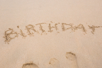 happy birthday written on the sand beach
