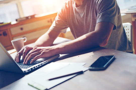 Man With Mobile Phone And Laptop In Working In Office. Intentional Sun Glare