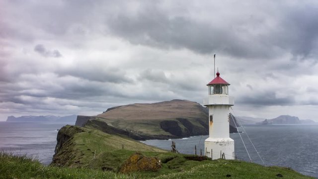 4K time lapse of a remote lighthouse with distance views of an island with steep cliffs, filmed on Mykines, Faroe Islands 