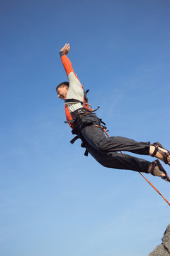 Man jumping off a cliff with a rope.