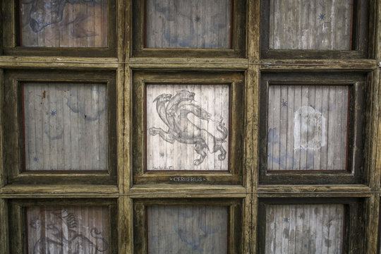 Old wooden ceiling with caissons. Each caisson - a mystical image. In the center - Cerberus, the infernal dog with three heads.