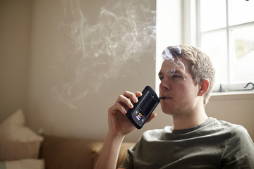 Young Man Using Vapourizer As Smoking Alternative