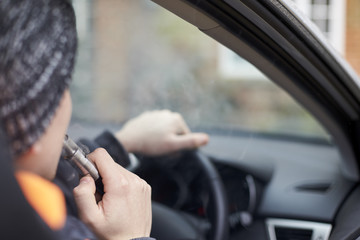 Close Up Of Young Man Sitting In Car Using Vapourizer