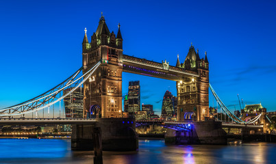 Fototapeta na wymiar Illuminated Tower Bridge in London after sunset with London’s financial district at the background