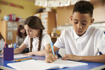 Two primary school pupils at their desks in class, close up