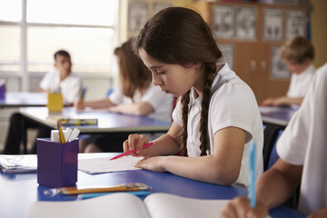 Primary school girl working at her desk in class