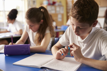 Two kids working at their desks in primary school, close up