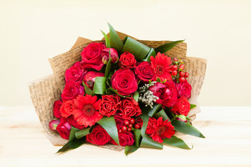 Closeup shot of red bouquet of roses, gerberas, peonies, pomegranates. Love and passion symbol. Anniversary gift. Birthday present for girl.