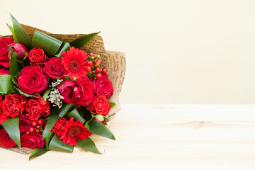 Red bouquet of roses, gerberas, peonies, pomegranates with copyspace. Love and passion symbol. Anniversary gift. Birthday gift for girl.