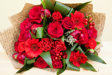 Closeup shot of red bouquet of roses, gerberas, peonies, pomegranates. Love and passion symbol. Anniversary gift. Birthday present for girl.