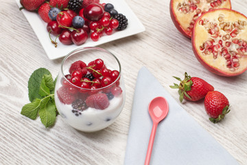 Vaso de yogur con frutos rojos. Grosellas, mora, frambuesas, fresas. sobre una mesa de madera blanca rústica. Vista superior