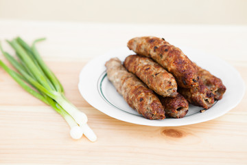 Lamb kebab on plate and onion on light wooden background with copyspace. Cuisine background. Eastern food. Street food. Hot grilled kebab. Weekend barbeque.