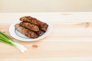 Lamb kebab on plate and onion on light wooden background with copyspace. Cuisine background. Eastern food. Street food. Hot grilled kebab. Weekend barbeque.