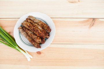 Lamb kebab on plate and onion on light wooden background with copyspace. Flat lay, top view. Cuisine background. Eastern food. Street food. Hot grilled kebab. Weekend barbeque.