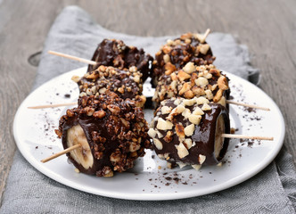 Frozen banana covered with chocolate and peanuts