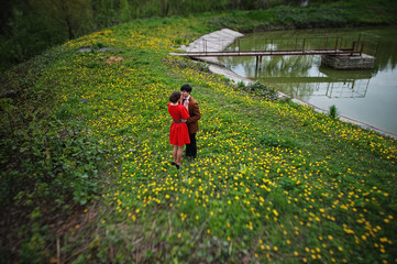 Couple hugging in love at yellow flowers field near lake and pon
