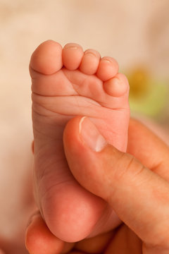 Foot of one week old baby in father\'s hand. Close up, vertical shot