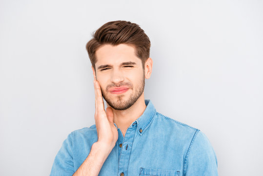Depressed ill man having toothache and touching cheek
