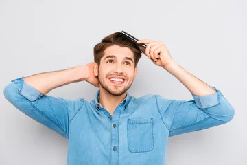 Fotobehang Kapsalon Portrait of handsome cheerful young man combing his hair