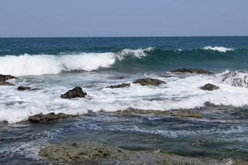 Fototapeta na wymiar 庄内浜の荒波（初夏）／山形県庄内浜の荒波風景を撮影した写真です。庄内浜は非常にきれいな白砂が広がる海岸と、奇岩怪石の磯が続く大変素晴らしい景観のリゾート地です。強風の日の海岸で、荒波を撮影した写真です。