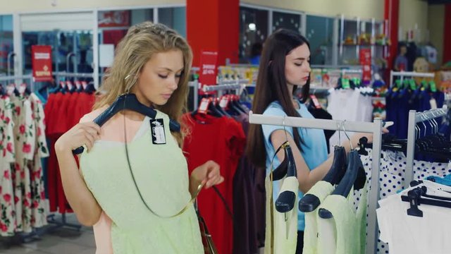 Women considering summer clothes on sale in the shop