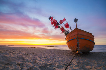 Zachód słońca nad morską plażą,kutry rybackie na piasku - obrazy, fototapety, plakaty