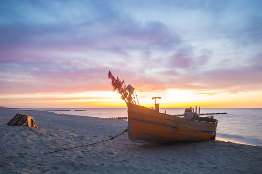 Fototapeta Zachód słońca nad morską plażą,kutry rybackie na piasku