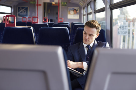 Businessman Commuting To Work Reading Newspaper On Train 