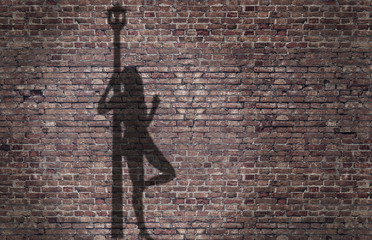 ombra di una prostituta appoggiata al lampione sul muro di mattoni 