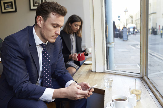 Businessman Using Mobile Phone Inside Coffee Shop