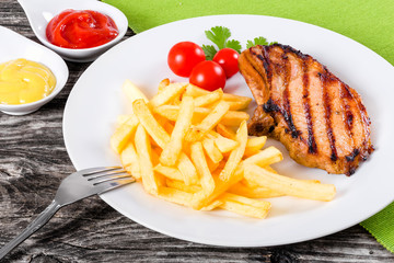 grilled pork chops on a white dish with french fries