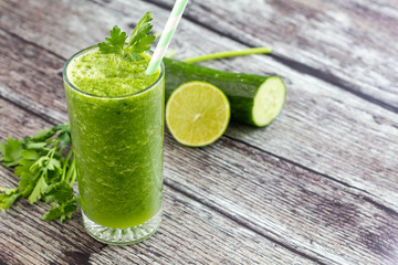 Green smoothie on wooden background with ingredients around it